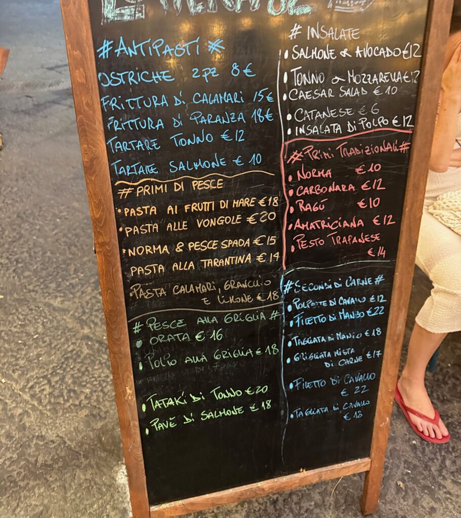 Tablica z menu przed lokalem w Katanii: owoce morza, pasta alla Norma i dania z koniny