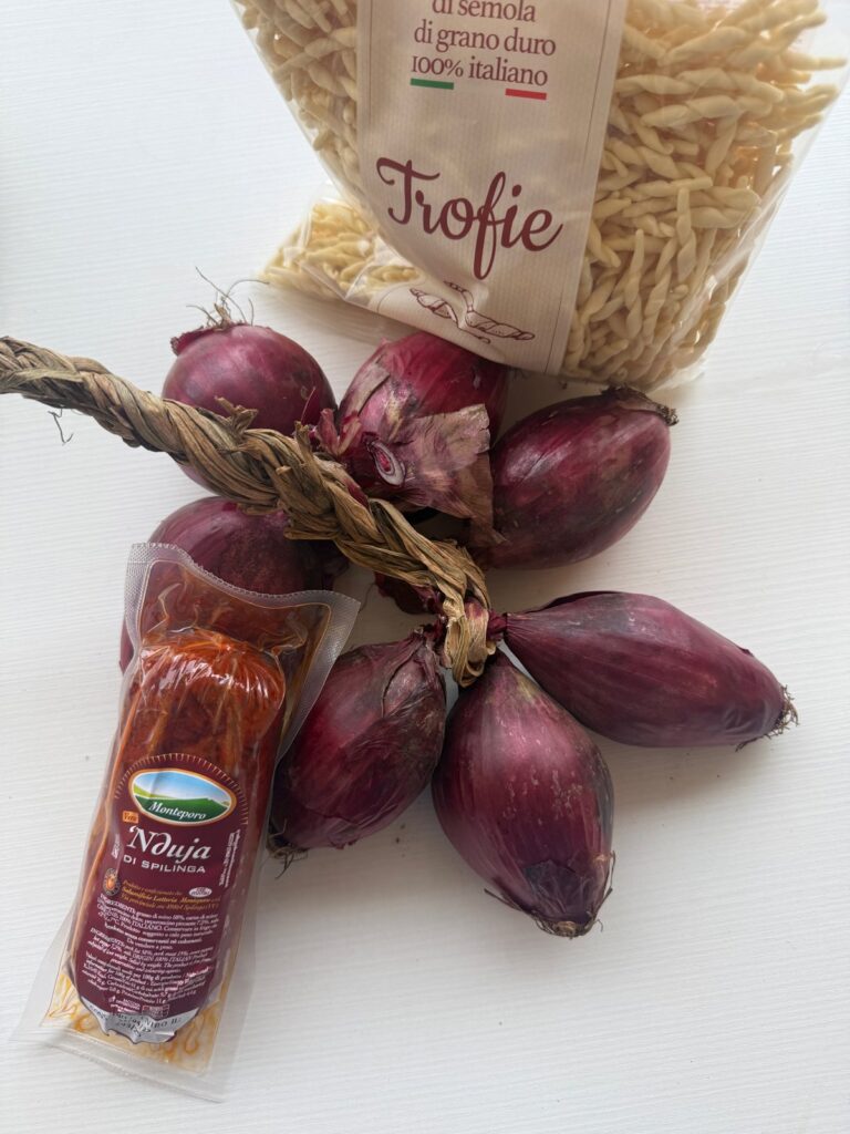 Warkocz czerwonej cebuli z Tropei, 'nduja di Spilinga w opakowaniu i paczka świeżych trofie