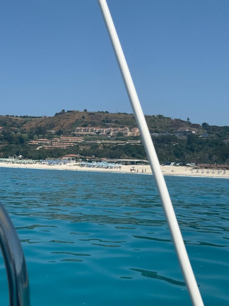 Plaża z parasolami w Zambrone widziana z pokładu łodzi stojącej poza strefą kąpieliska